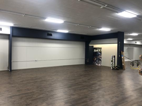 A spacious gym interior featuring various exercise equipment and open areas for workouts and fitness classes.